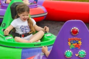 A child excitedly navigate a bumper car inside a bright inflatable attraction.