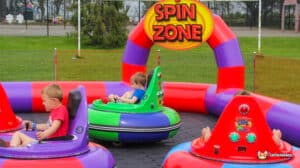 Cheerful young children rides an inflatable bumper car, surrounded by bright colors in a fun-filled play environment.