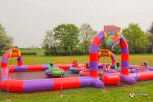 People playing in inflatable bumper cars on a grassy field, creating a fun and energetic atmosphere.