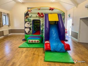 Jungle bouncy castle on wooden floor in hall.