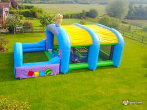 A soft play inflatable arena highlighted by a teddy bear on top, offering a safe and fun area for kids to enjoy.
