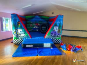Automobile themed bouncy castle indoors on hard surface.