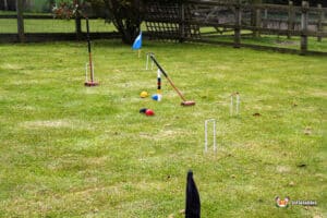 A croquet setup on a grassy lawn featuring colored balls, mallets, and wickets, ready for a fun outdoor game.