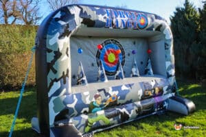 An inflatable target range with colorful targets, shaped cones, and a camouflage design, set in a grassy outdoor area.