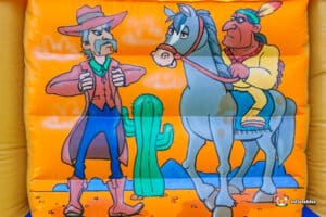 Cartoon characters decorate a lively Western-themed bouncy castle, creating a fun atmosphere for kids to enjoy.
