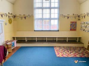 small room with wooden storage and carpets.