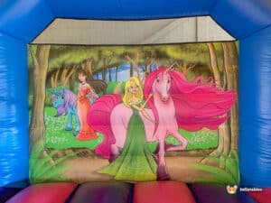 A colorful bouncy castle featuring princesses and unicorns, set against a bright blue sky, inviting children to play.