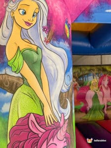 A colorful unicorn bouncy castle featuring a princess, inviting children to play and enjoy a magical experience.