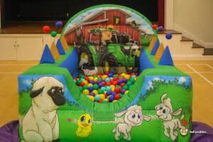 A ball pit featuring playful farm animals and a toy tractor, surrounded by a sea of colorful plastic balls.