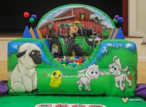 A lively ball pit with assorted farm animals and a toy tractor, surrounded by colorful balls for an engaging play experience.