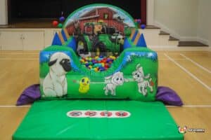 A ball pit filled with bright plastic balls, showcasing farm animals and a toy tractor for a fun playtime scene.