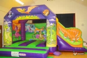 A whimsical bouncy castle featuring dinosaurs and animals, designed for children's amusement and active play.