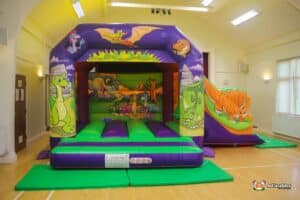 A colourful bouncy castle featuring various dinosaurs and animals, inviting children to play and have fun.
