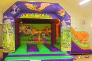 A vibrant bouncy castle adorned with dinosaur and animal designs, perfect for children's entertainment and enjoyment.