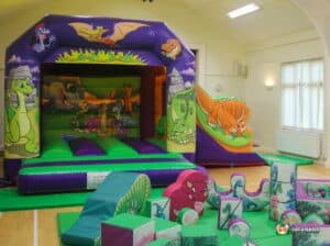 Indoor play area showcasing a bouncy castle alongside an assortment of soft play shapes for children's entertainment and fun