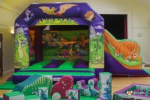 Dinosaur Bouncy castle with soft play items and ball pool for children's birthday parties.