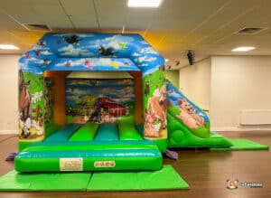 A stunning farm-themed bouncy castle featuring a slide, perfect for children's outdoor play and entertainment.
