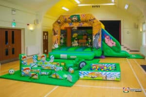 A cheerful play area featuring a farm-themed inflatable and a variety of soft play toys for young children.