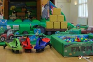 A farm-themed play area for children, featuring a barn, animal sculptures, and interactive play structures.