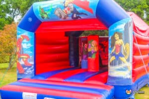 A colorful bouncy castle themed around superheroes, labeled "Hero Biff and Bash," inviting children to play.