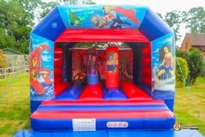 A vibrant bouncy castle with a superhero theme, titled "Hero Biff and Bash," designed for children's entertainment.