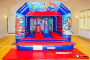 A superhero-themed bouncy castle featuring bright colors and comic-style graphics, perfect for children's entertainment.