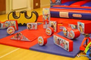 A large inflatable bouncy castle featuring superhero-themed soft play toys and colorful items for children to enjoy.