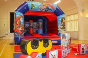 An inflatable bouncy castle with superhero soft play toys, providing a lively and engaging play area for children.
