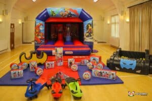 A vibrant superhero-themed inflatable bouncy castle filled with toys, inviting children to play and have fun.