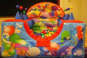 A colorful bouncy castle adorned with balloons and festive decorations, inviting children to play and enjoy.