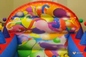 A vibrant bouncy castle surrounded by balloons and decorations, creating a cheerful atmosphere for kids' entertainment.