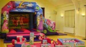 A colorful inflatable bounce house with fairy-tale characters, surrounded by vibrant play blocks and a ball pit.