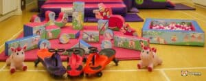 A colorful indoor play area features unicorn-themed soft play blocks, ride-on toys, and a ball pit, inviting children to play and explore.