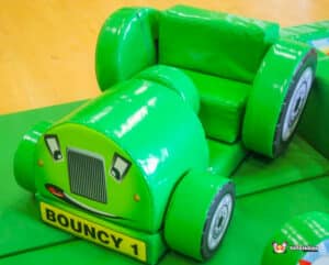Green toy tractor labeled "Bouncey 1," part of a farm soft play set, designed for safe indoor play.