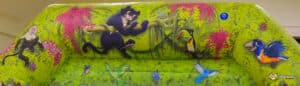 A vibrant inflatable jungle scene featuring monkeys, toucans, and colorful birds amidst lush greenery and blooming flowers.