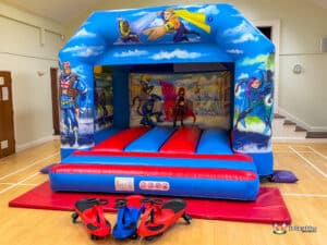 A red and blue hero-themed bouncy castle featuring plasma cars for children to enjoy.