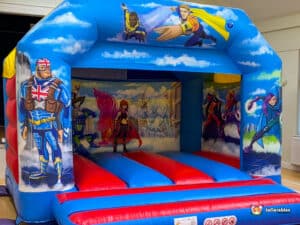 A vibrant red and blue bouncy castle designed with a hero theme, complete with plasma cars for added fun