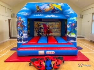 A playful hero-themed bouncy castle in red and blue, including plasma cars for an exciting experience for children.