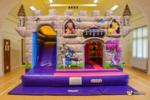 A vibrant bouncy castle styled as a princess castle, complete with a slide and plasma cars for added fun.