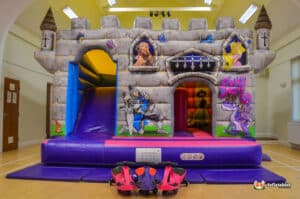 A bright bouncy castle with an attached slide, resembling a castle, offering a fun play space for children.