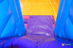 Colorful blue and purple inflatable slide, designed for children's entertainment at outdoor events or parties.