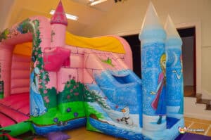 A vibrant inflatable bouncy castle themed around princesses, complete with colorful turrets and playful designs.