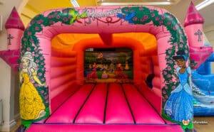 A vibrant princess-themed bouncy castle adorned with images of princesses, perfect for children's parties and events.