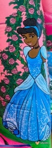 A cheerful Disney princess balloon displaying a princess, positioned above a fun bouncy castle, perfect for celebrations.
