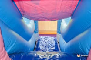 A colorful blue and pink inflatable slide featuring a large slide for children to enjoy outdoor play.