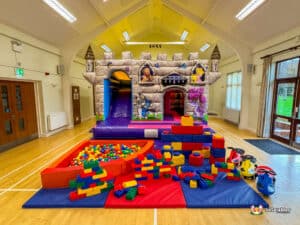 A vibrant castle-themed play area featuring a colorful bouncy castle and a tall slide for children to enjoy.