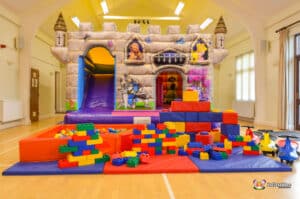 A castle-themed playground featuring a bouncy castle and a slide, providing a fun space for children to play and explore.