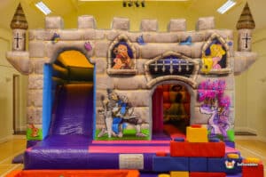 A whimsical castle play area with a bright bouncy castle and a slide, inviting children to engage in playful activities.