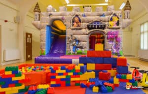 A play area designed like a medieval castle, showcasing a bouncy castle and a slide for children's enjoyment.