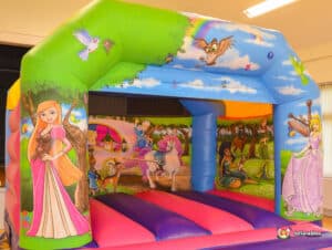A vibrant bouncy castle adorned with images of princesses, inviting children to jump and play at a festive gathering.